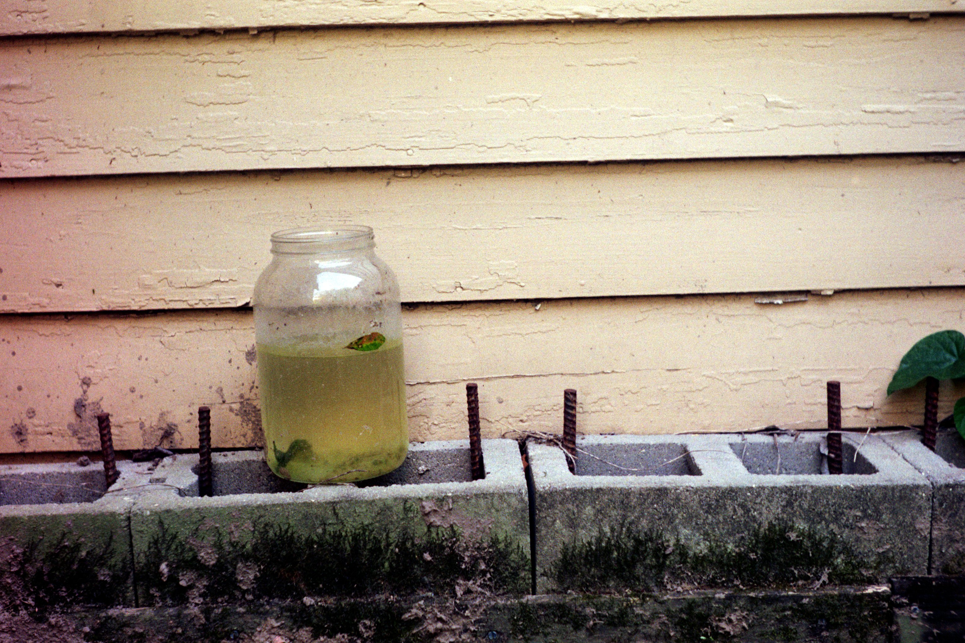 a jar full of dirty water sitting on some bricks