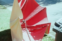 A broken red umbrella on the curb